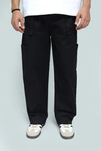 Person wearing black cargo pants on a light gray background